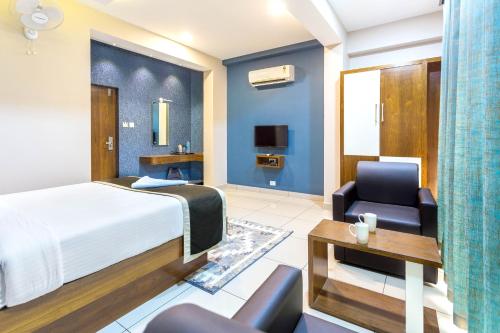 a hotel room with a bed and a chair at Nextel Inn, Calicut in Kozhikode