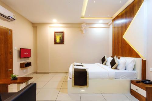 a hotel room with a bed and a tv at Nextel Inn, Calicut in Kozhikode