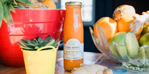 a bottle of orange juice next to a bowl of oranges at Kite Basecamp Langebaan in Langebaan