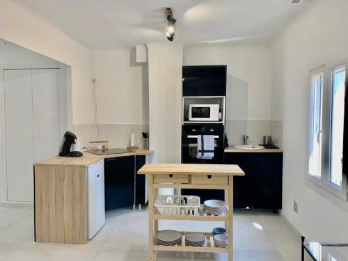 a kitchen with black and white counters and a microwave at T2 bis cosy climatisé, Intra Muros Avignon in Avignon