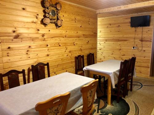 two tables and chairs in a room with wooden walls at Sadyba Domashniy zatyshok in Pilipets