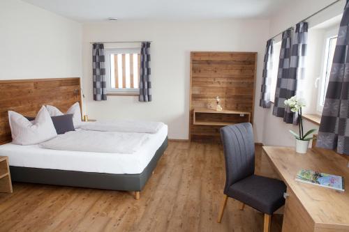 a bedroom with a bed and a desk and a chair at Ferienbauernhof Köpf in Füssen