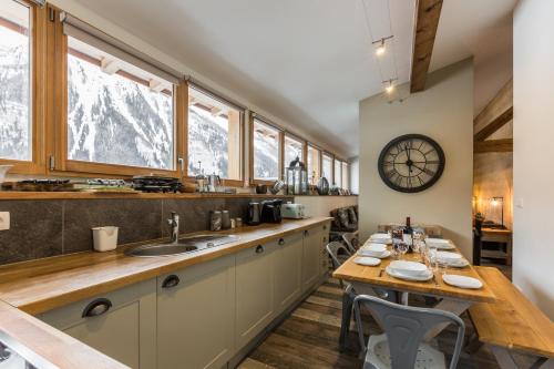 une cuisine avec une table et une horloge au mur dans l'établissement Loft Apartment High Rimaye - Mont Blanc Views, Close to Brevent, à Chamonix-Mont-Blanc