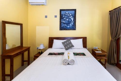 a bedroom with a large white bed with a mirror at Dekwah Homestay in Ubud