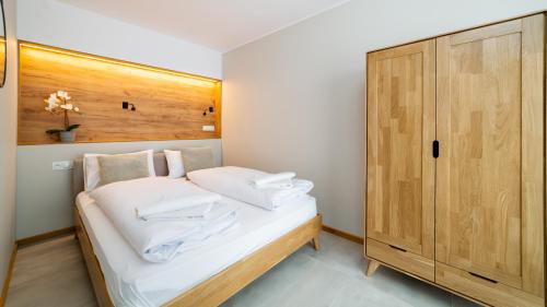 a small bedroom with a bed and a wooden cabinet at Triventi Mountain Residence, Sun & Snow in Karpacz