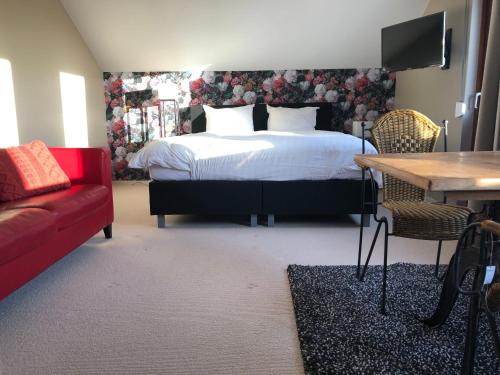 1 dormitorio con cama, mesa y sofá rojo en De grote Zeearend, en Aardenburg