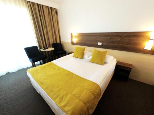 a hotel room with a large bed with yellow sheets at Zenith - Top Country Line - Conference & Spa Hotel in Mamaia