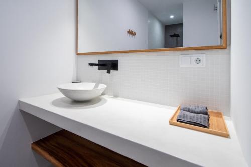 La salle de bains est pourvue d'un lavabo blanc et d'un miroir. dans l'établissement Apartamentos Son de Cadiz, à Cadix
