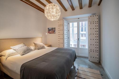 Un dormitorio con una cama grande y una lámpara de araña. en Apartamentos Son de Cadiz en Cádiz