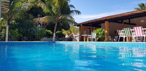 a swimming pool with chairs and a house at Vivenda Xawã in Corumbau