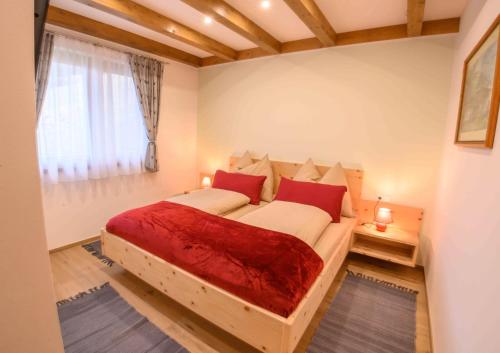 1 Schlafzimmer mit 2 Betten mit roten Kissen und einem Fenster in der Unterkunft Chalet Waldhof in Flattach