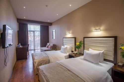 a hotel room with two beds and a television at Hotel Orion Tbilisi in Tbilisi City