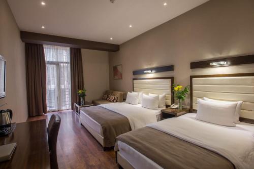 a hotel room with two beds and a couch at Hotel Orion Tbilisi in Tbilisi City
