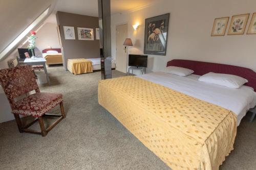 a bedroom with a bed and a chair and a desk at Hotel Prins Boudewijn in Knokke-Heist