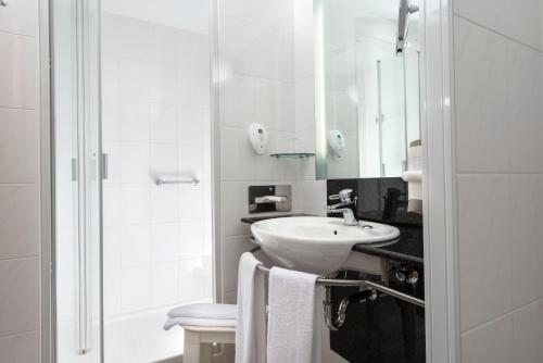 y baño blanco con lavabo y ducha. en Radisson Blu Fürst Leopold Hotel, en Dessau