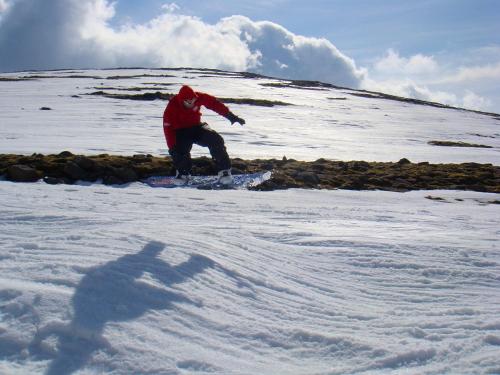 a person riding a snowboard down a snow covered slope at Ravenscraig Guest House in Aviemore