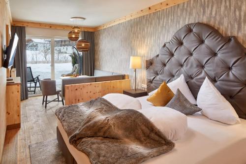 Schlafzimmer mit einem großen Bett mit einem Kopfteil aus Leder in der Unterkunft Vitalpina Hotel Magdalenahof in Santa Maddalena in Casies