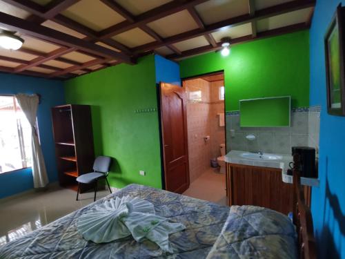 una camera da letto con pareti verdi, un letto e un lavandino di Los Tucanes Lodging a El Castillo