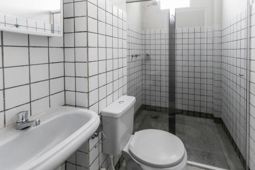 a white bathroom with a toilet and a sink at Hotel Araxá in Araxá