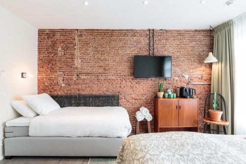 een slaapkamer met een bed en een bakstenen muur bij Hotel Dwars in Amsterdam