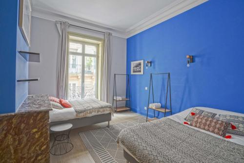 a blue room with two beds and a window at NOCNOC - Le Terracotta in Montpellier