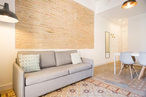 uma sala de estar com um sofá e uma parede de tijolos em Design Apartments by Olala Homes em Hospitalet de Llobregat