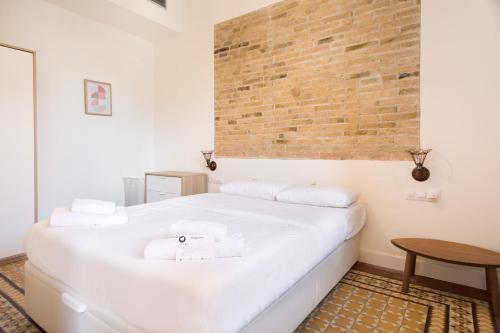 uma cama branca num quarto com uma parede de tijolos em Design Apartments by Olala Homes em Hospitalet de Llobregat