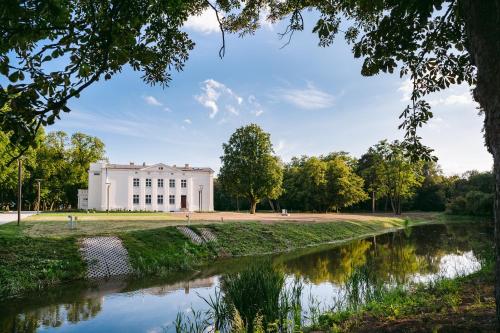 a white building with a river in front of it at Kasztanowy Pałac in Swadzim