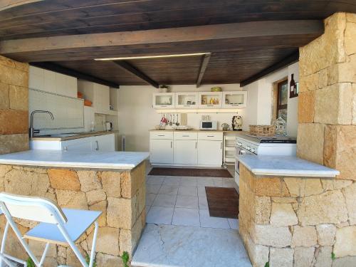 a kitchen with white cabinets and a stone wall at Villa Plemmyria in Syracuse