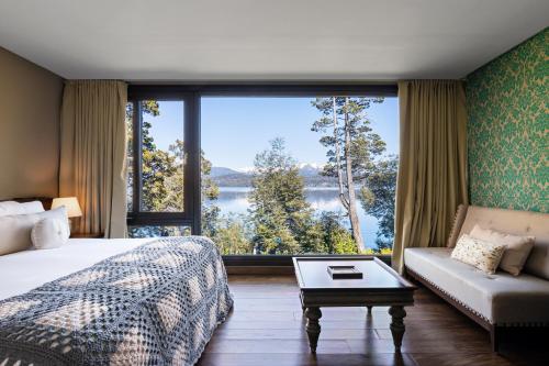 a bedroom with a bed and a couch and a large window at Calfuco Wine Hotel & Spa in Villa La Angostura