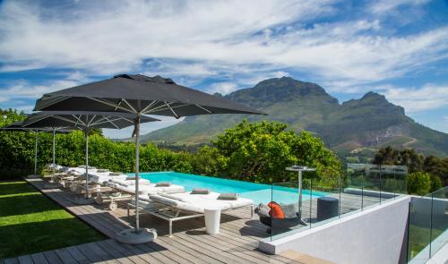 a pool with an umbrella and chairs and a swimming pool at Clouds Estate in Stellenbosch