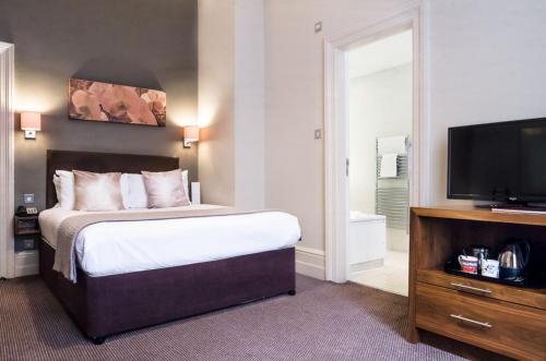 a bedroom with a bed and a flat screen tv at The Met Hotel Leeds in Leeds