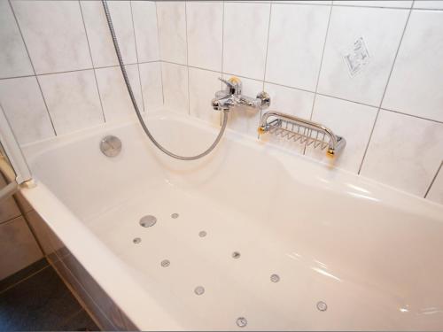 a bath tub with a shower in a bathroom at Hotel Ambiente in Saas-Fee
