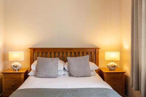 a bedroom with a bed with two lamps on tables at Roydon Marina Village Hotel in Roydon