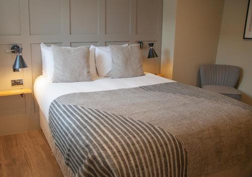 a bedroom with a large bed and a chair at The Kings Arms Hotel in Malmesbury