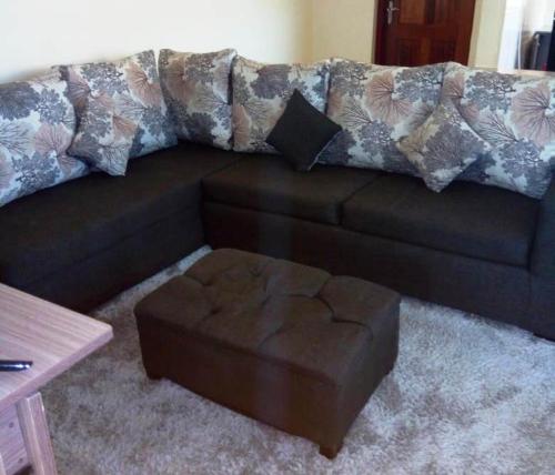 a brown couch with a ottoman in a living room at BLUE NILE 9 - SUNSET HOLIDAY APARTMENTS, SHANZU - Mombasa in Mombasa