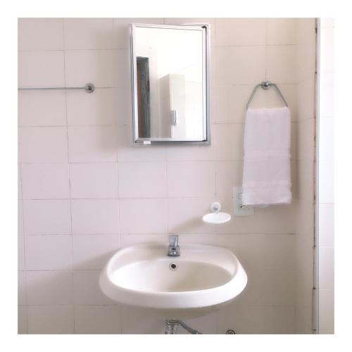 a white bathroom with a sink and a mirror at Morada do Sol Guest House in Búzios