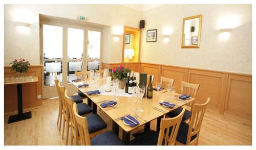 a dining room with a long table and chairs at The Woodhouse Hotel in Largs