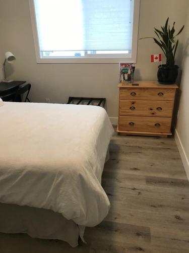 1 dormitorio con 1 cama, vestidor y ventana en Your home away from home, en Kelowna