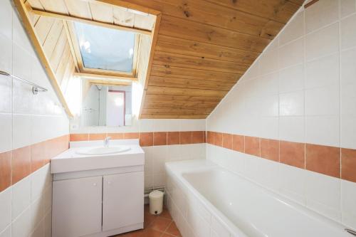 La salle de bains est pourvue d'un lavabo, d'une baignoire et d'une fenêtre. dans l'établissement Residence Les Chalets de Puy Saint Vincent - maeva Home, à Puy-Saint-Vincent
