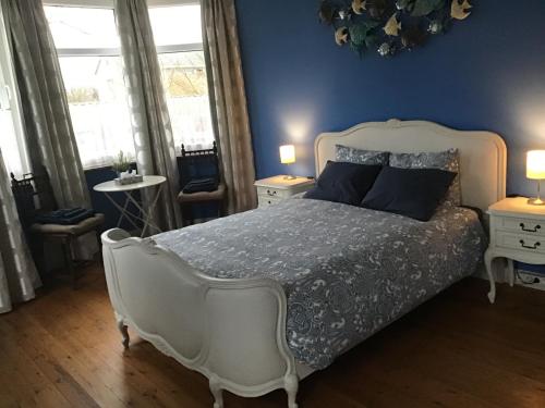 a bedroom with a white bed with blue walls and windows at Room Feliz in Zele
