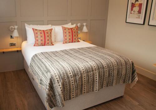 a bedroom with a large bed with white sheets and pillows at The Kings Arms Hotel in Malmesbury