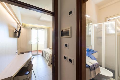 a bathroom with a door leading to a bedroom at Hotel Cavour in Cesenatico