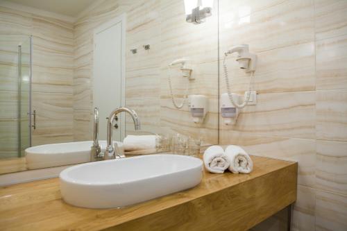 a bathroom with a white sink and a tub at Hotel Perla in Rogoznica