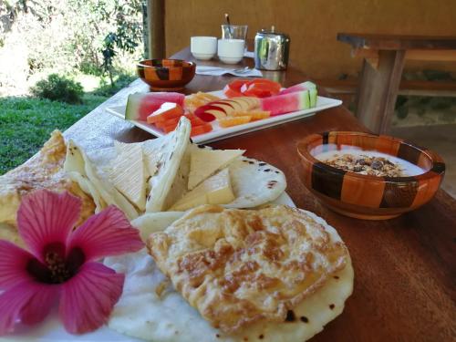 a table with a plate of food with cheese and fruit at EYA Ecolodge in San Isidro