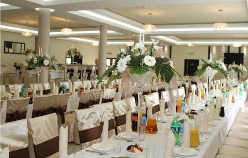 a long table with white chairs and vases with flowers at Motel-Restauracja Ballaton in Chustki