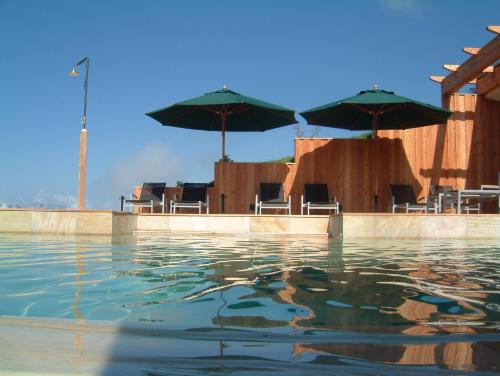 - une piscine d'eau avec des chaises et des parasols dans l'établissement Der Zirmerhof, à Redagno