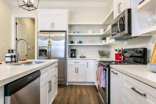 una cucina con armadi bianchi e frigorifero in acciaio inossidabile di St Charles Ave Living Near Hot Spots and Restaurants a New Orleans