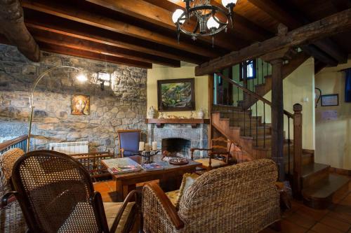 a living room with a table and a stone fireplace at Hotel El Carmen in Ribadesella