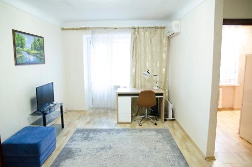 ein Wohnzimmer mit einem Schreibtisch und einem Fenster in der Unterkunft Apartments in the park area of the Dnipro in Dnipro